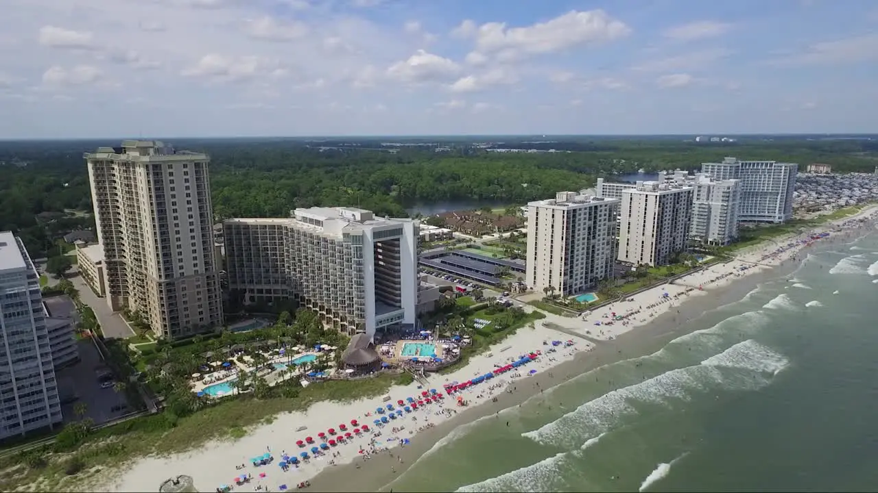 Slow panning shot of tall resorts on the beach in summer