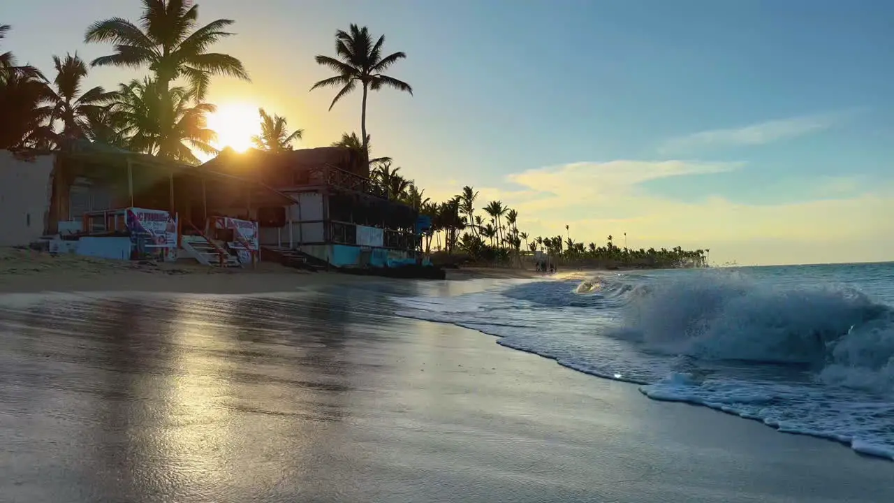 panning left shot from Caribbean to vendor lines beach at sunset with palm trees and waves