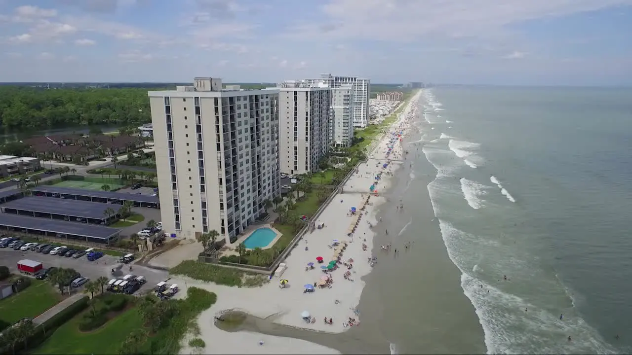 Flying towards tall ocean-front resorts near the beach in summer