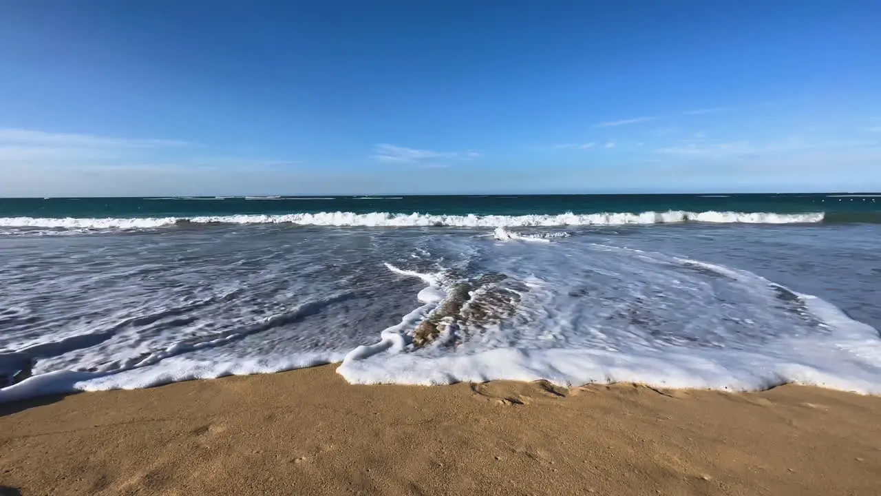 water level view of Caribbean waves crashing onto the beach and gently retreating back to the ocean