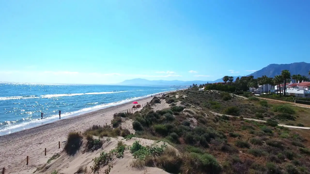 drone flying over sand dunes next to a sunny beach