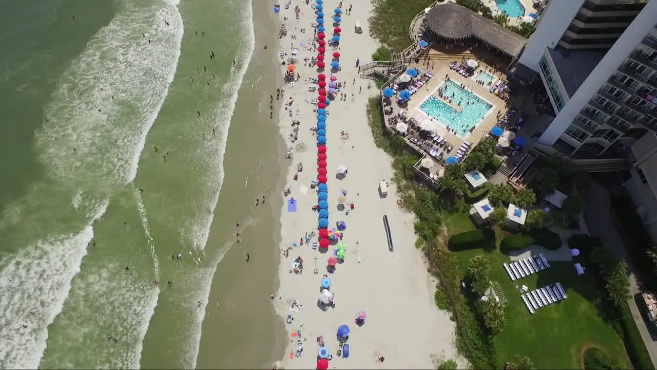 Static bird's eye view of people on beach sunbathing under umbrellas