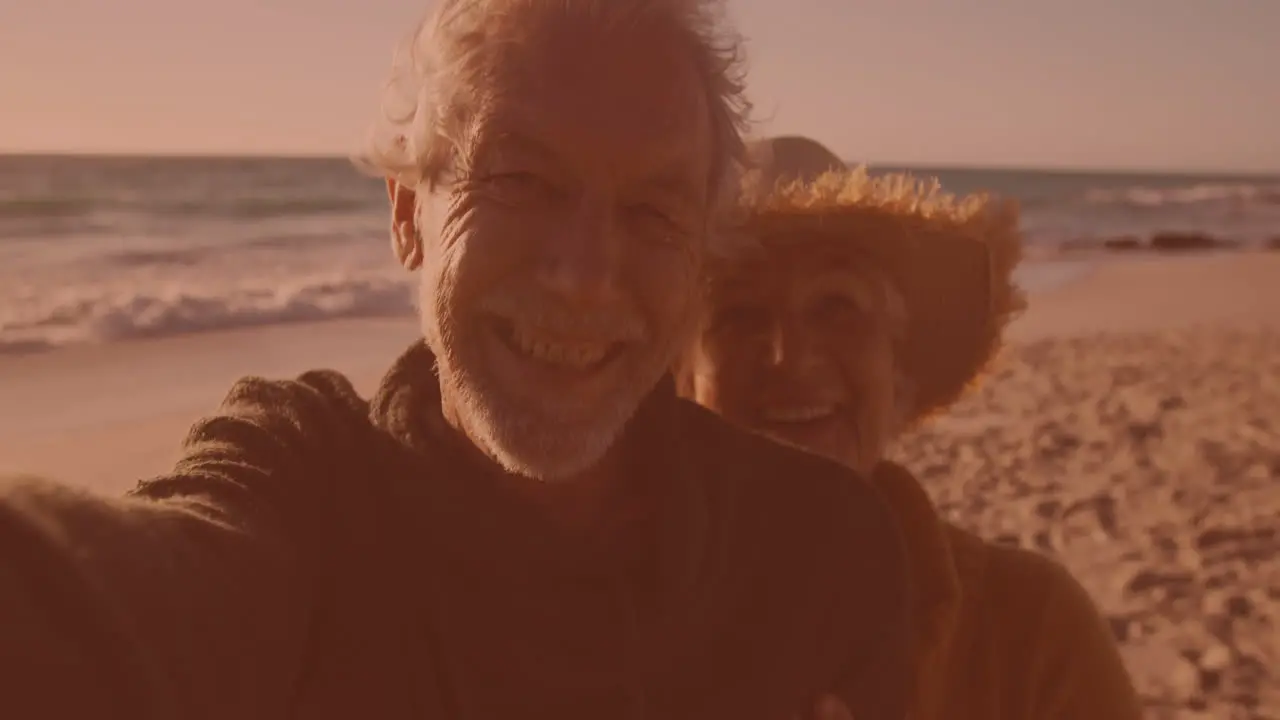 Happy caucasian senior couple talking a selfie together at the beach