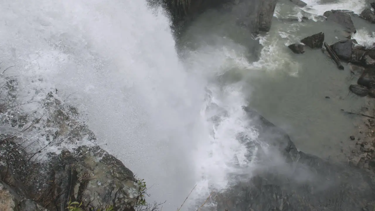 Slow motion video following the water of a waterfall as it falls down to the rocks below