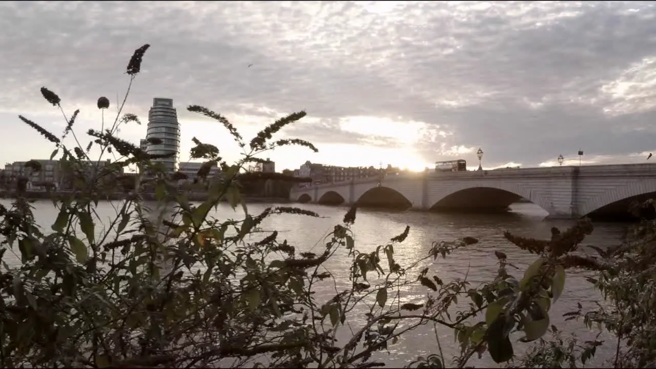 View of London at sunset with a double decker bus driving on the bridge