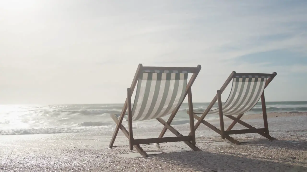 Two empty deckchairs standing on beach at sunset