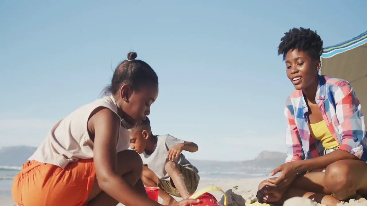 African american mother daughter and son playing in the sand on the beach