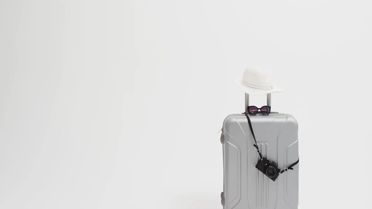 Close up of suitcase camera sunglasses and sunhat with copy space on white background