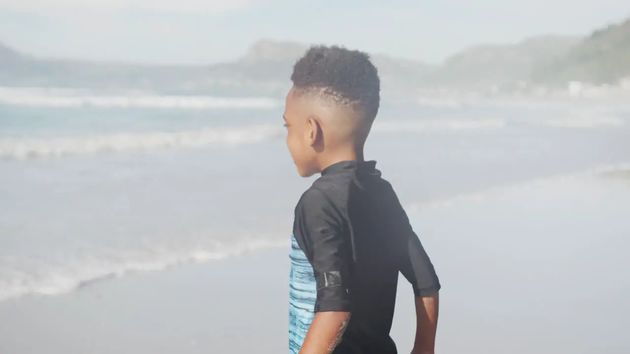 African american young boy jumping and enjoying at the beach