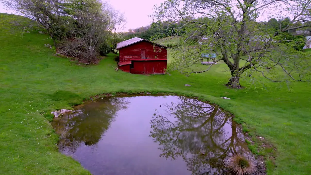 aerial push over farm pond into red barn near boone and blowing rock nc north carolina