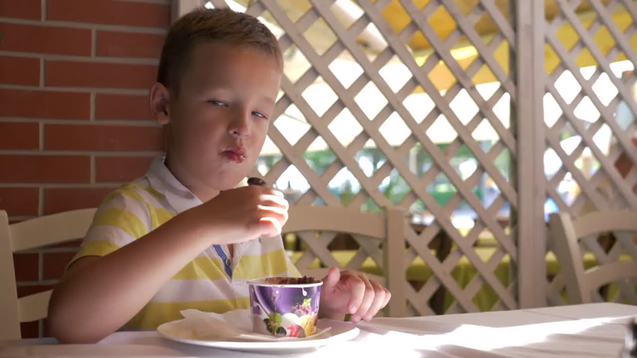 Little sweet tooth enjoying ice cream dessert in summer cafe