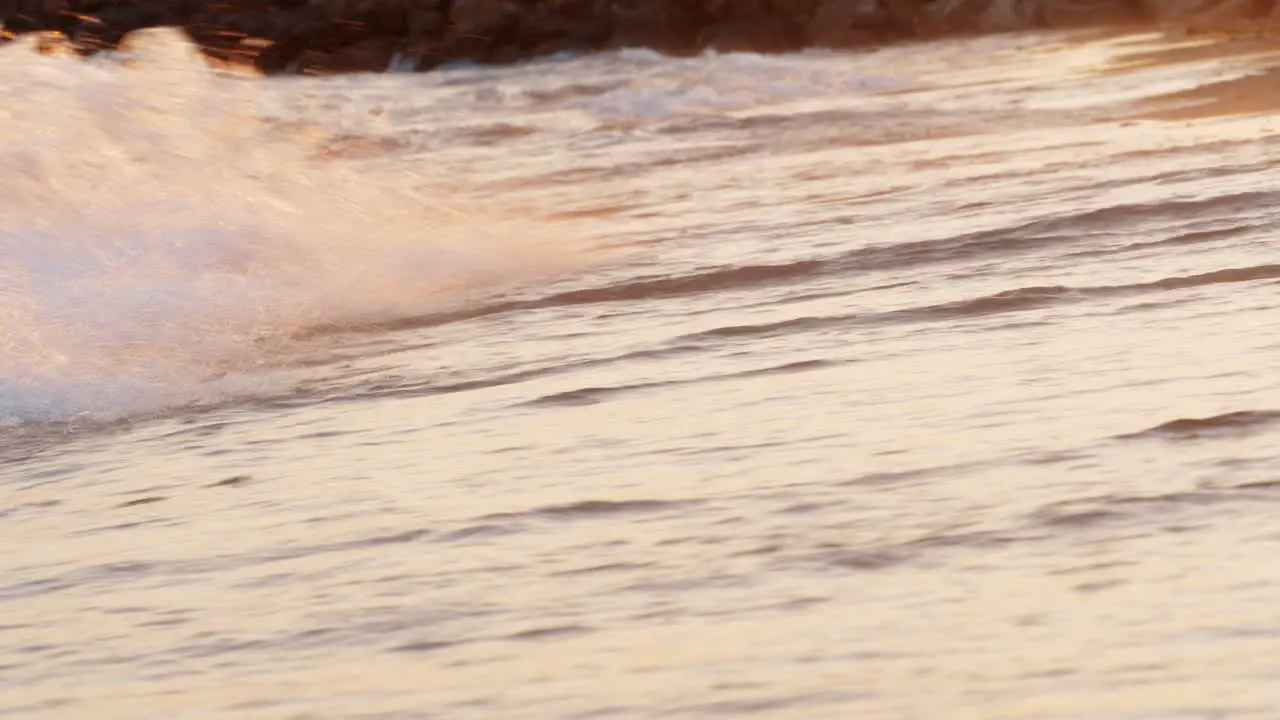 Sunset scene of foamy sea waves rolling in on the shore