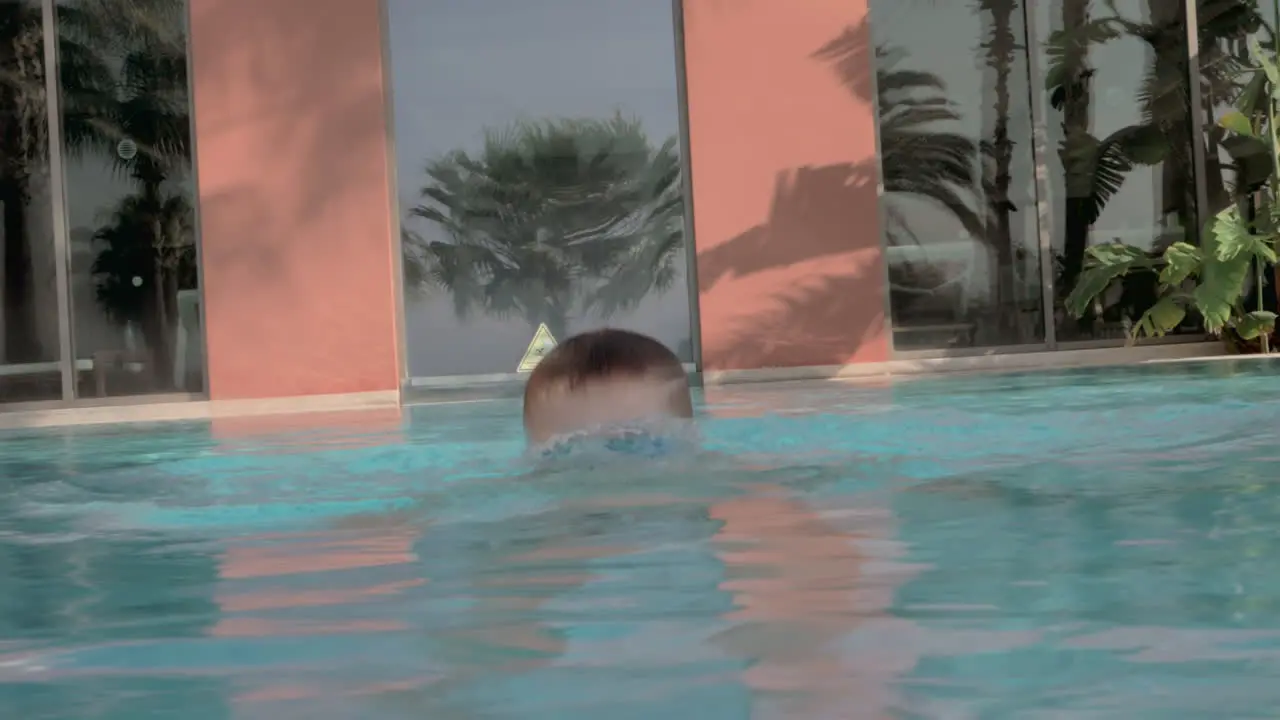 Child bathing in outdoor swimming pool He diving and coming to the surface