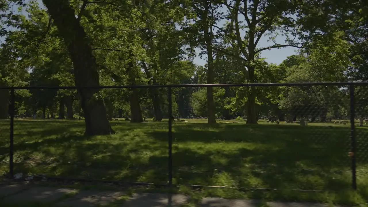 Panning shot of fence with Lake View Cemetery in the background on a sunny summer day