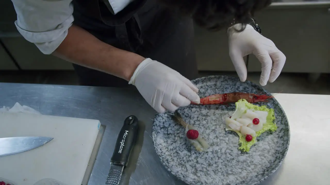 A professional chef preparing a plate of prawns in his kitchen