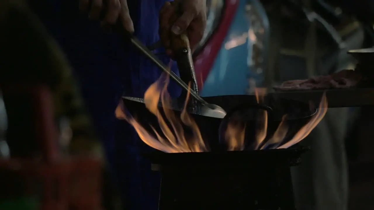 Man cooking noodle dish in wok on open fire Thailand