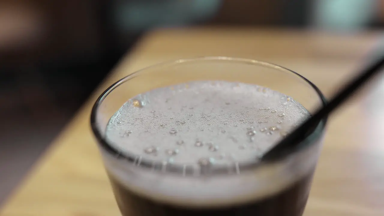 Pouring refreshing fizzy drink into glass with straw