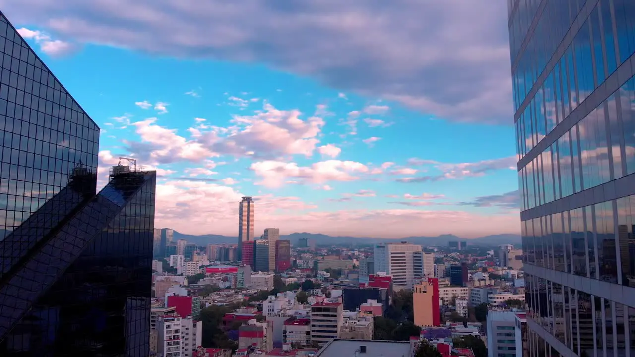 Drone shot cityscape between tall buildings in Mexico morning light cloudy sky clear view sunrise