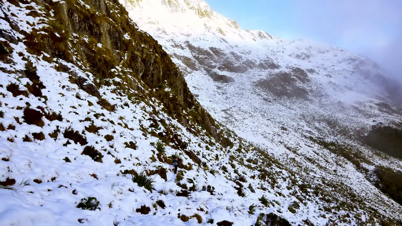 Solo adventurous woman trekking the snowy steep mountainous terrain