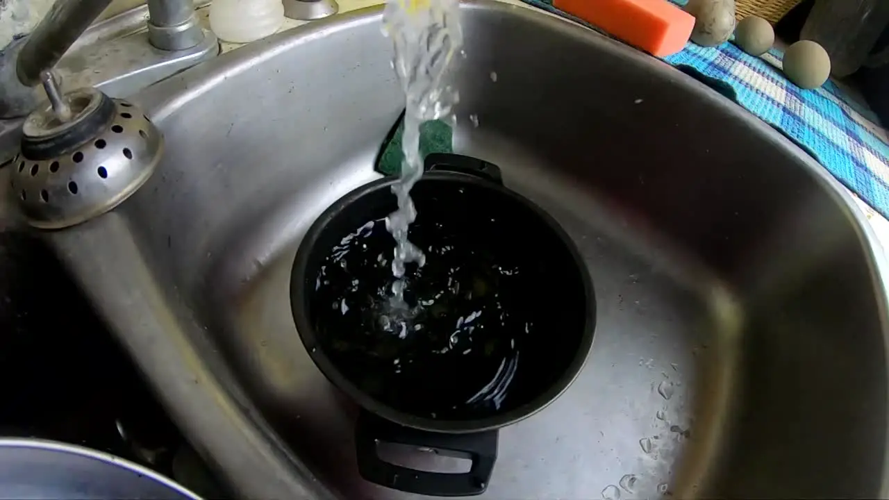 SLOW MOTION Water running from a tap into a pot in the kitchen sink