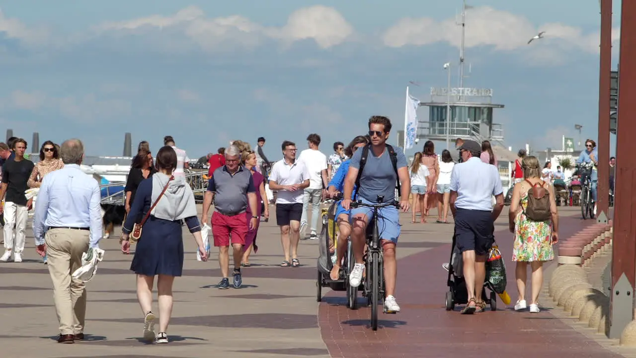 People Walking And Biking On The Promenade Of Knokke-Heist Beach On A Sunny Summer Day During The Pandemic Coronavirus In Flanders Belgium