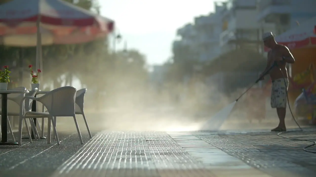 Man washing sidewalk in the morning