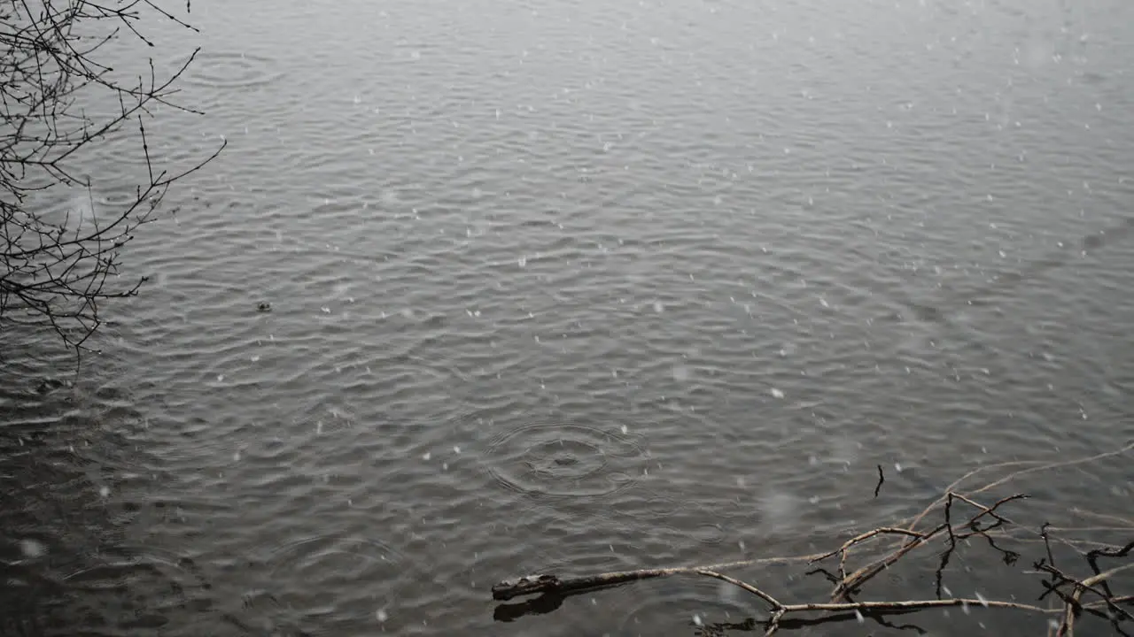 Huge snow flakes create splashes in water as they fall in slow motion