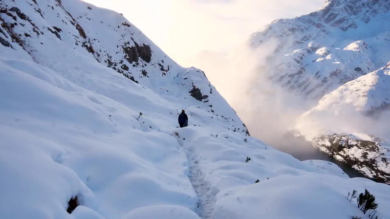 Solo backpacker trekking through thick blanket of snow over mountains on Routeburn track