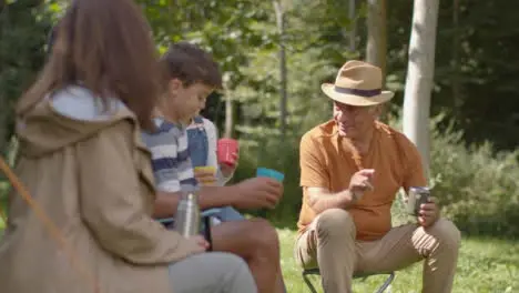 Tracking Shot of Family On Camping Trip Sitting and Talking by Their Tents 02