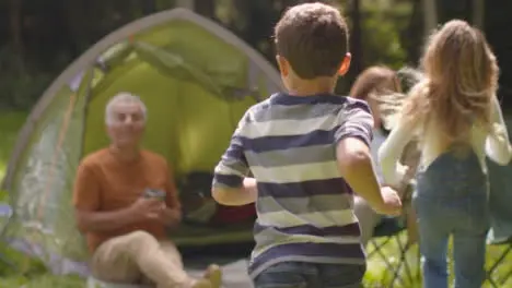 Tracking Shot Following Young Children Running to Their Grandparents On Camping Trip