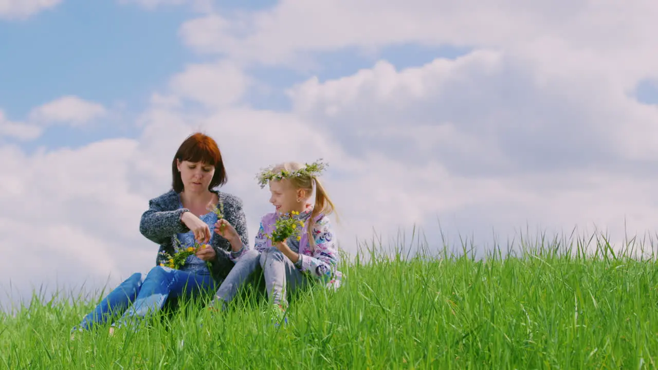 A Middle-Aged Woman With Her Daughter Wreathes A Wreath Of Wild Flowers Together