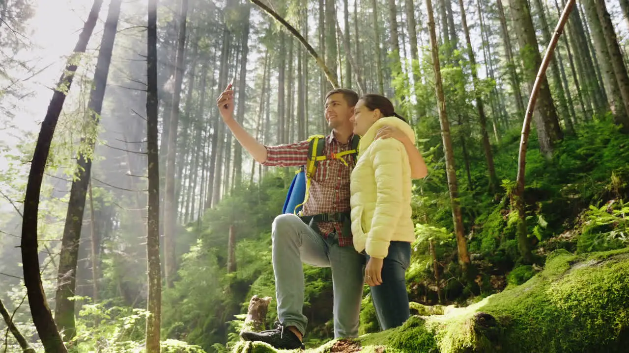 A Couple In Love Of Travelers With Backpacks Are Photographed In The Forest The Rays Of The Morning 