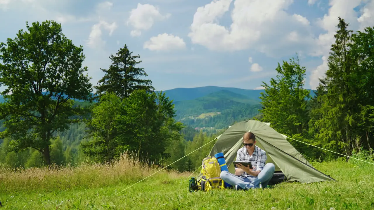 A Young Male Tourist Uses A Laptop While Camping Near A Tent 1