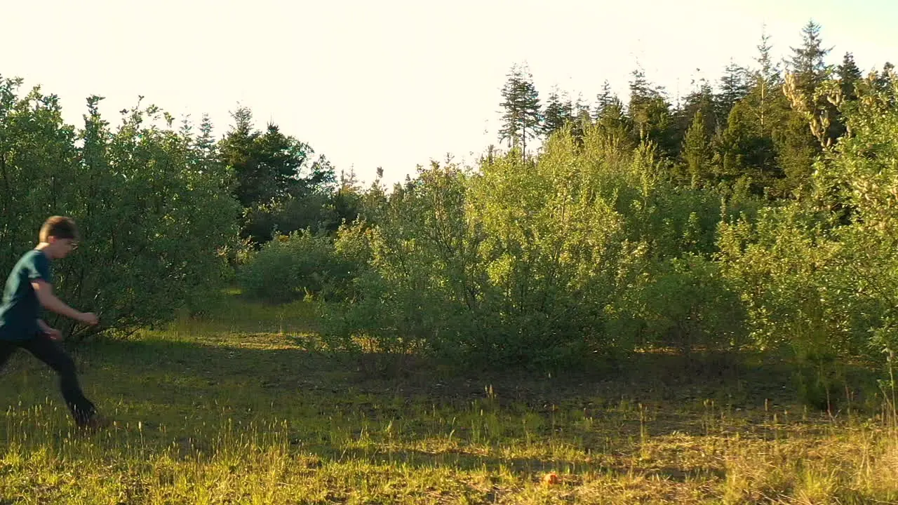 Athletic teenage boy doing flips outdoors in green nature