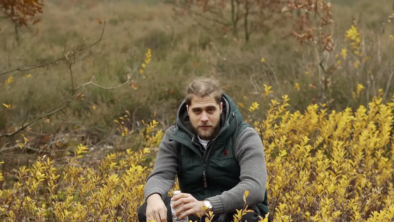 Man smoking a sigaret while sitting and resting in the autumn forest