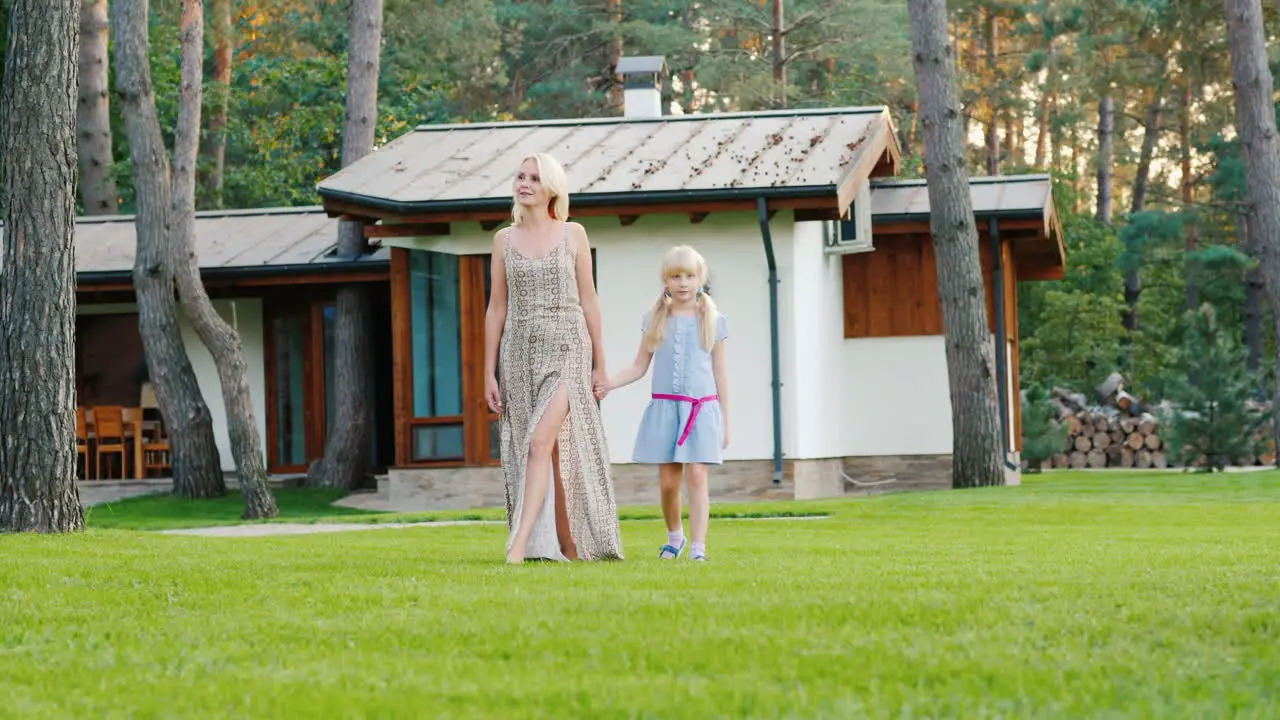 A Young Mother And Daughter Are Walking Around The Lawn Near Their House Slow Motion Video