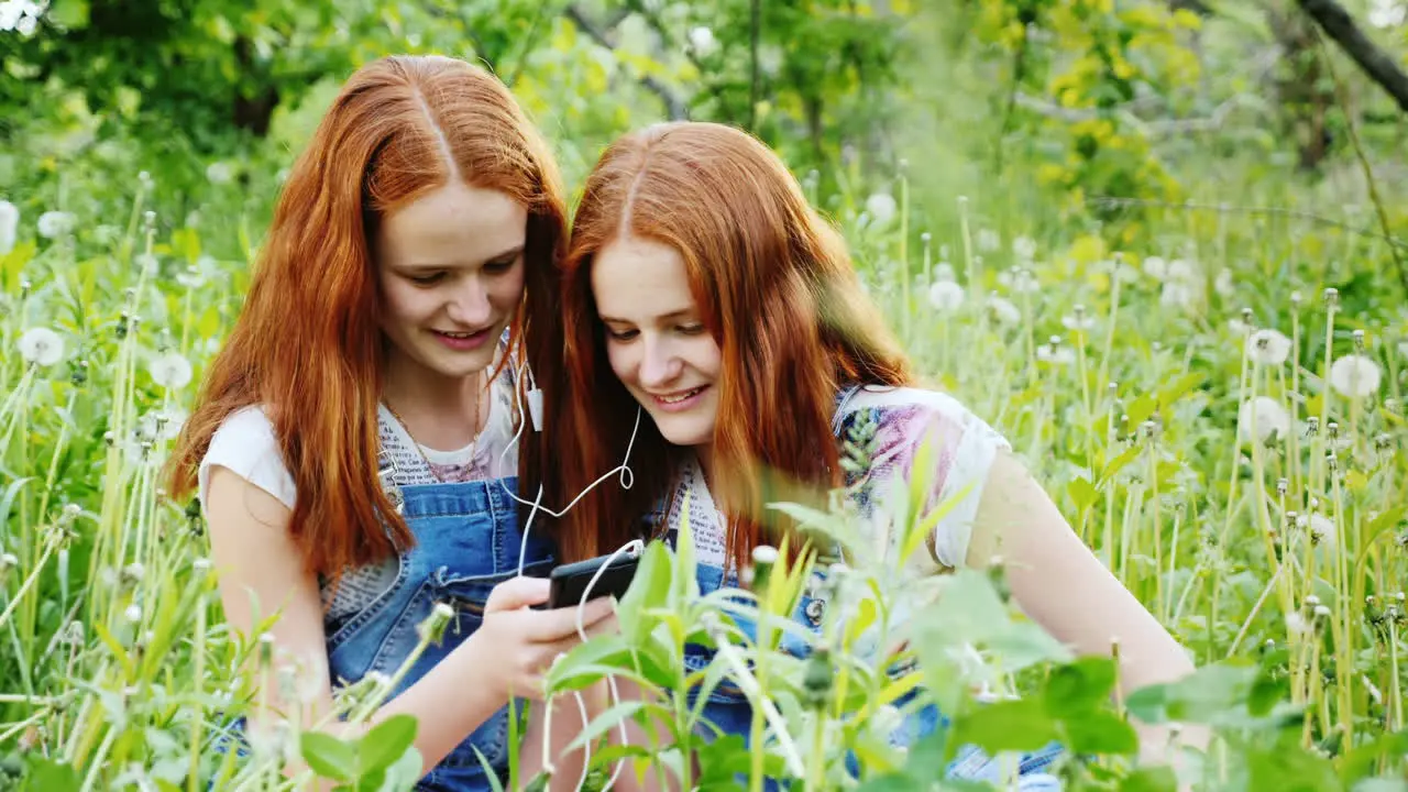 Two Cool Twins Girls Are Listening To Music Outdoors