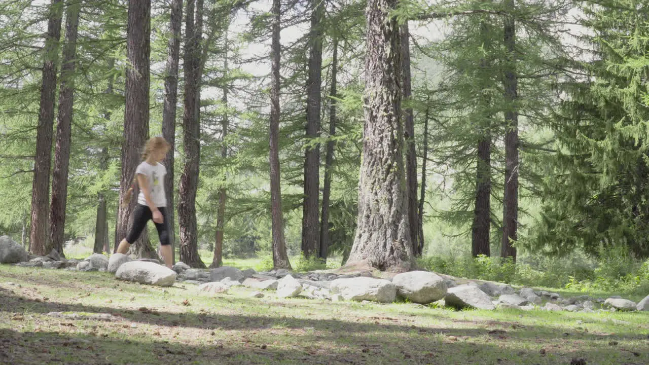 Little girls walks through rocks in a forest 4K