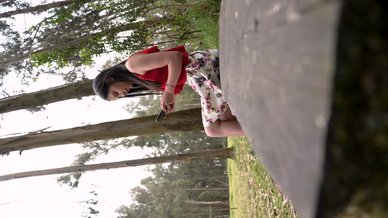 Low angle shot of a beautiful brunette woman sitting on a wooden bench in a forest