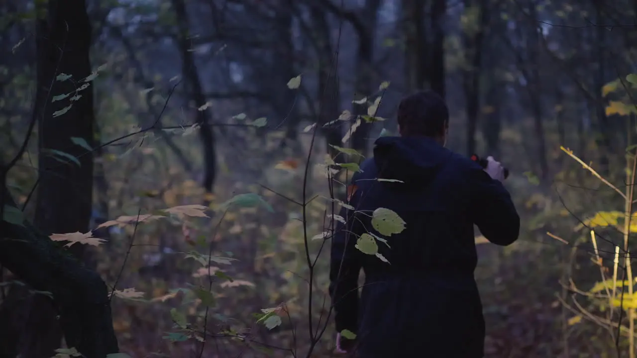 A Man In A Hood With A Flashlight In His Hand Walks Through A Dark Forest Search For A Man