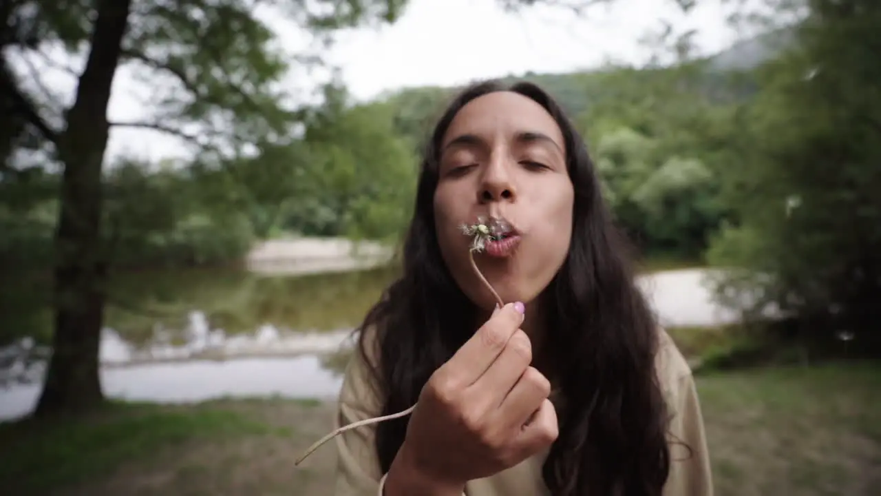 Lovely mixed-race woman blows and disperse seeds of a dandelion