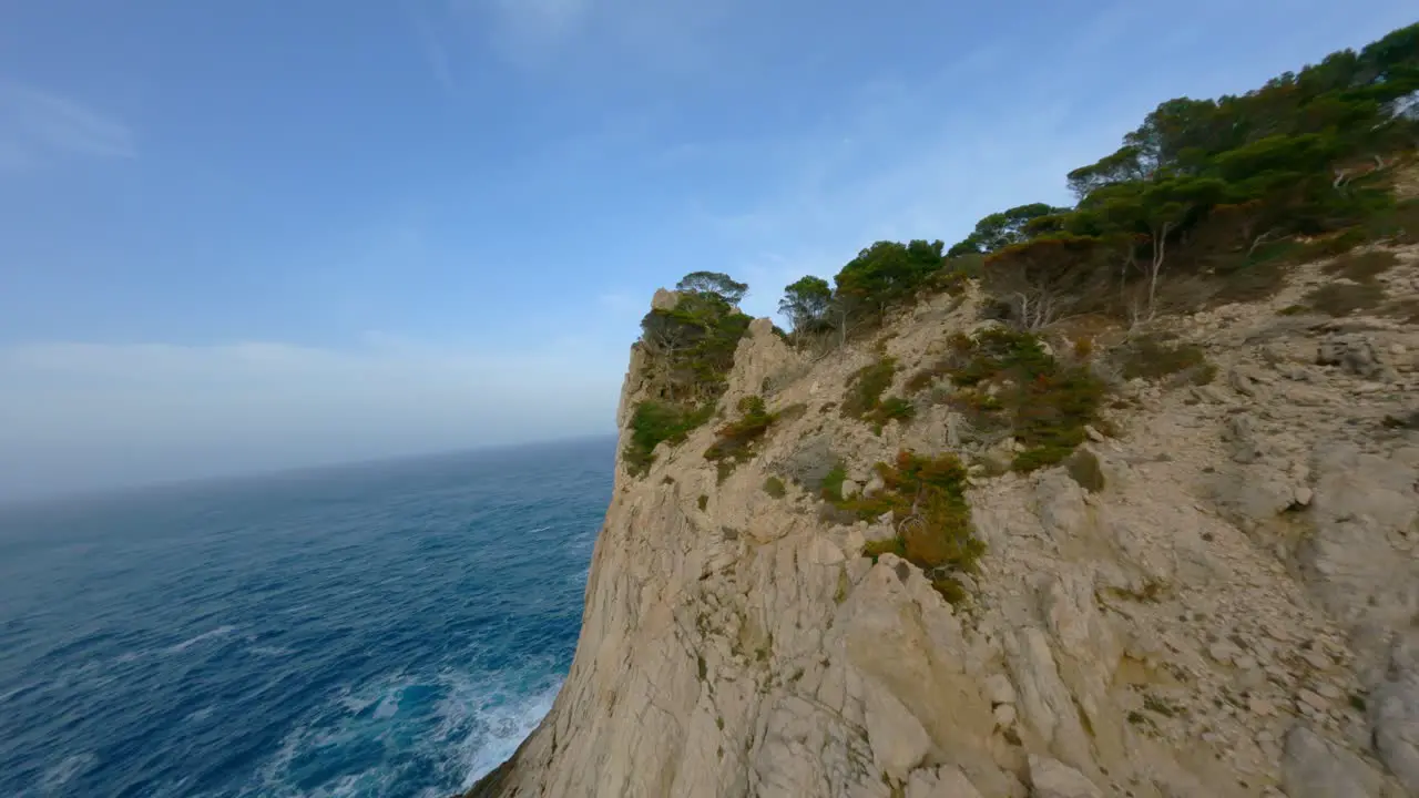 FPV Drone flying over rocky cliffs in Mallorca and through trees towards the great ocean