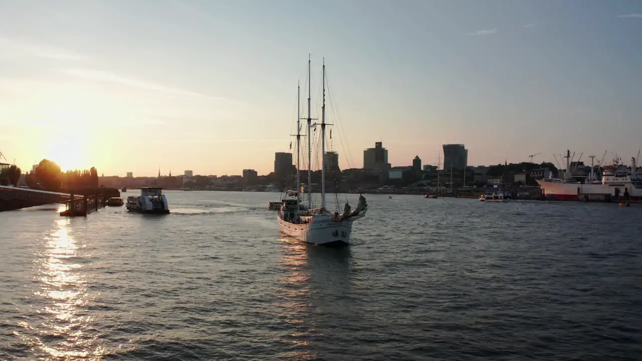 Sailboat in Hamburg Harbour sailing during golden hour next to the Elbphilharmonie and the lion king