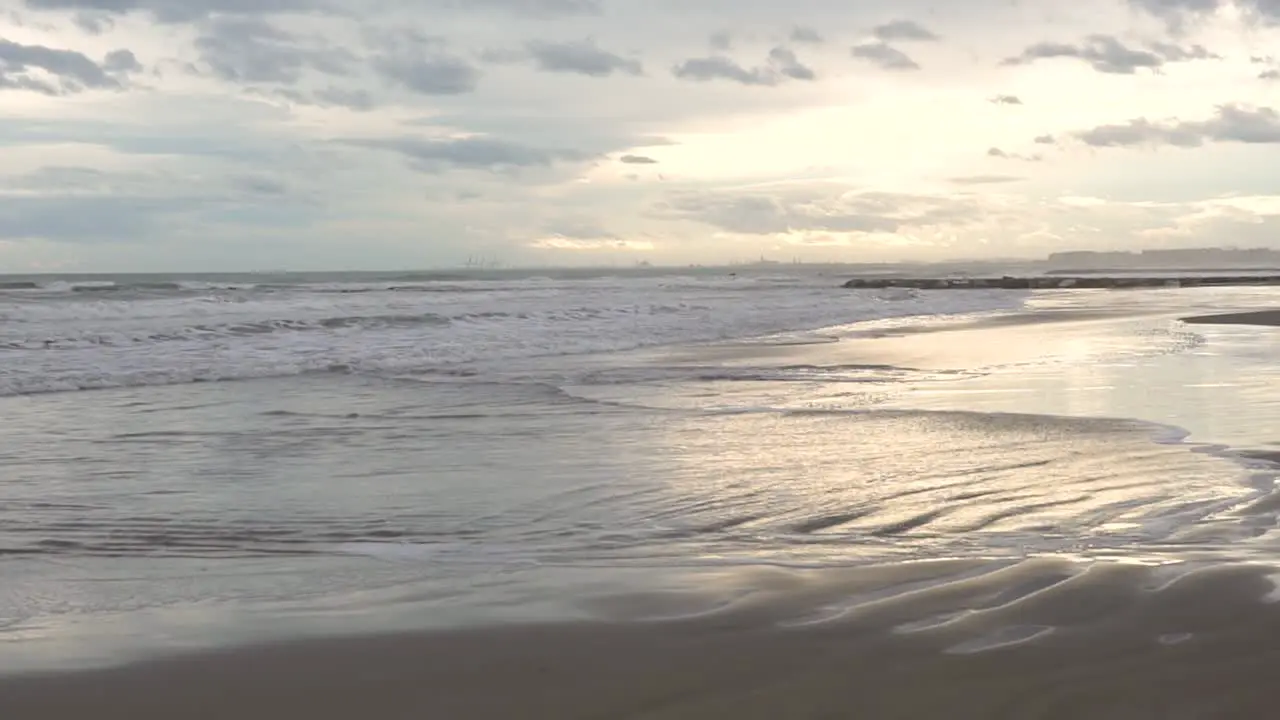 Slow motion sea wave on the sand at sunset