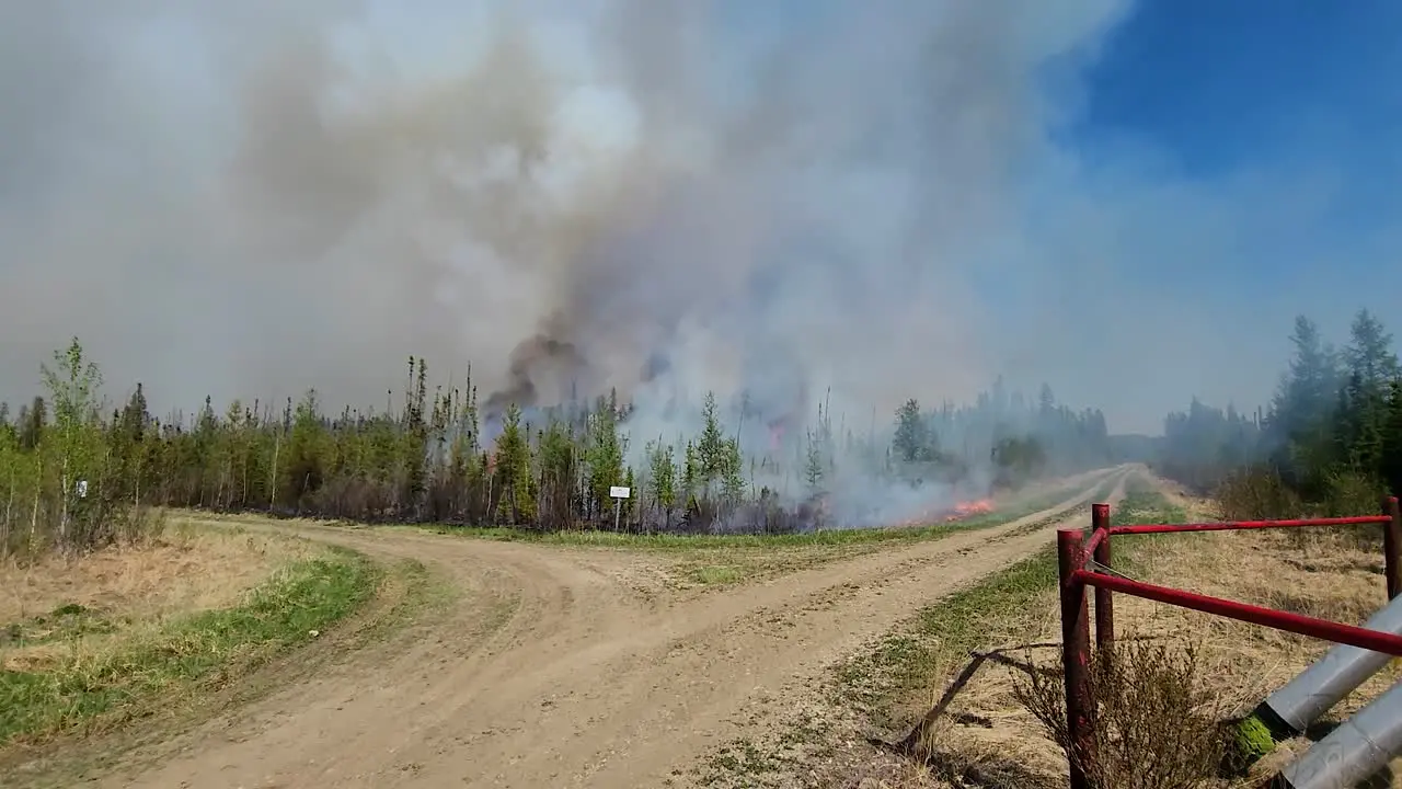 Canada wildfire burning along dirt road black smoke Alberta Canada