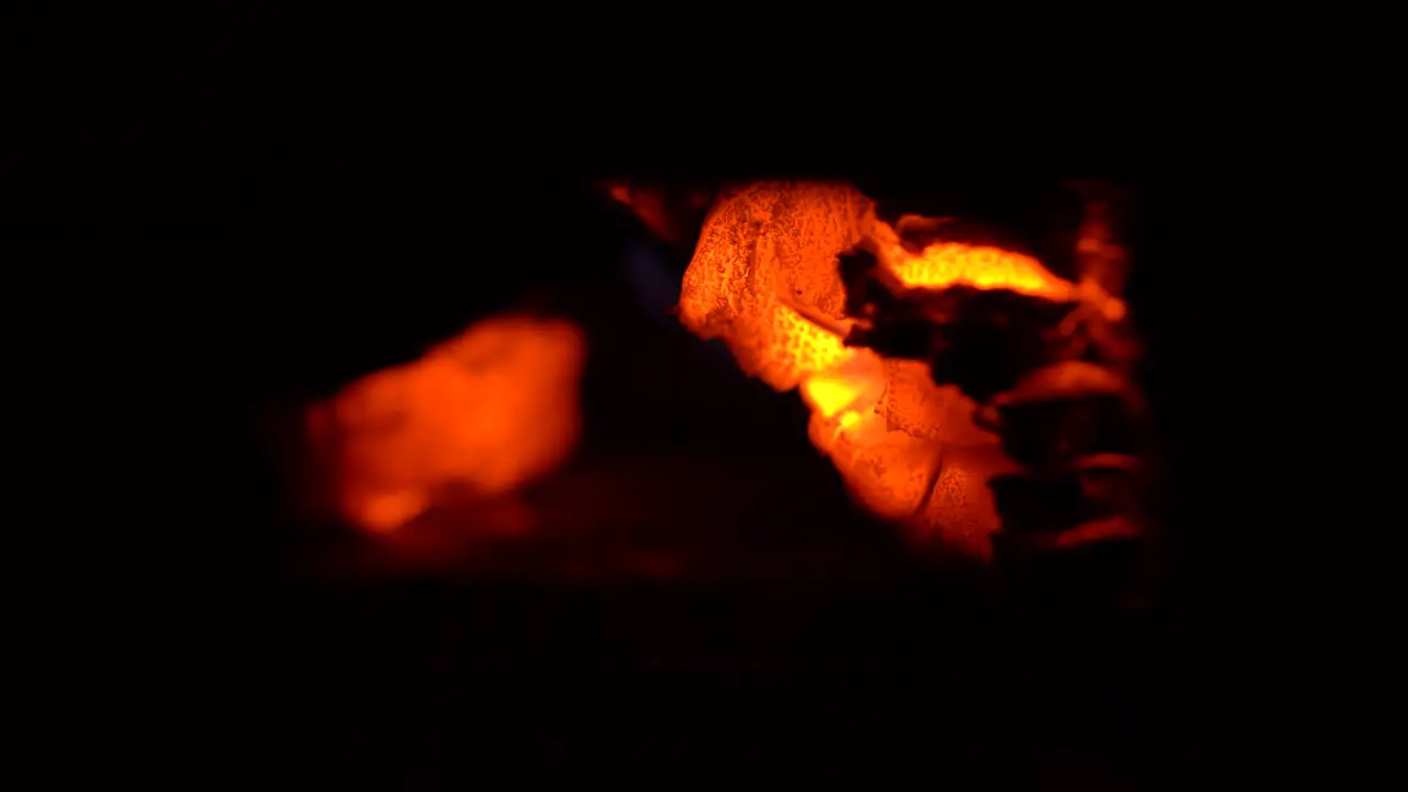 Close up macro of a wood fire with glowing embers moving and falling