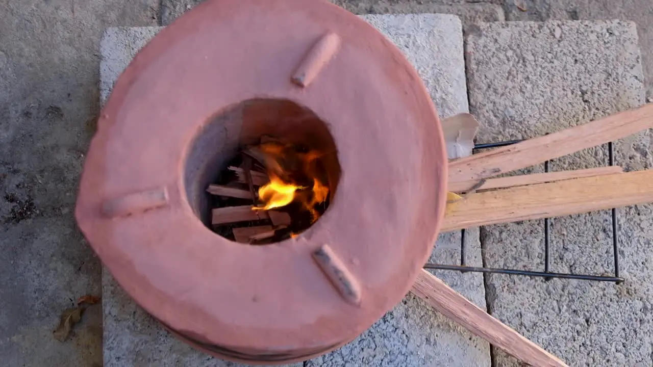 Clay wood burning cooking stove top down view inside the cooker with kindling and flames ready to cook food