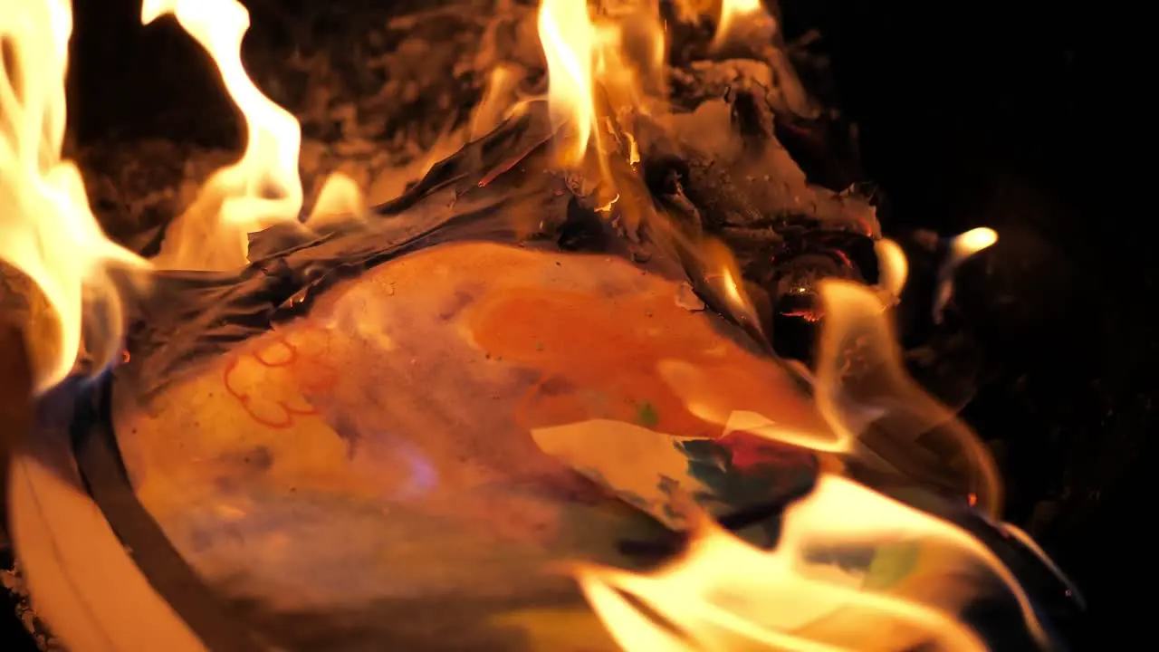 Fire burning with a kid's childhood butterfly paper art project burning up in a house fire pit in 4k 60fps