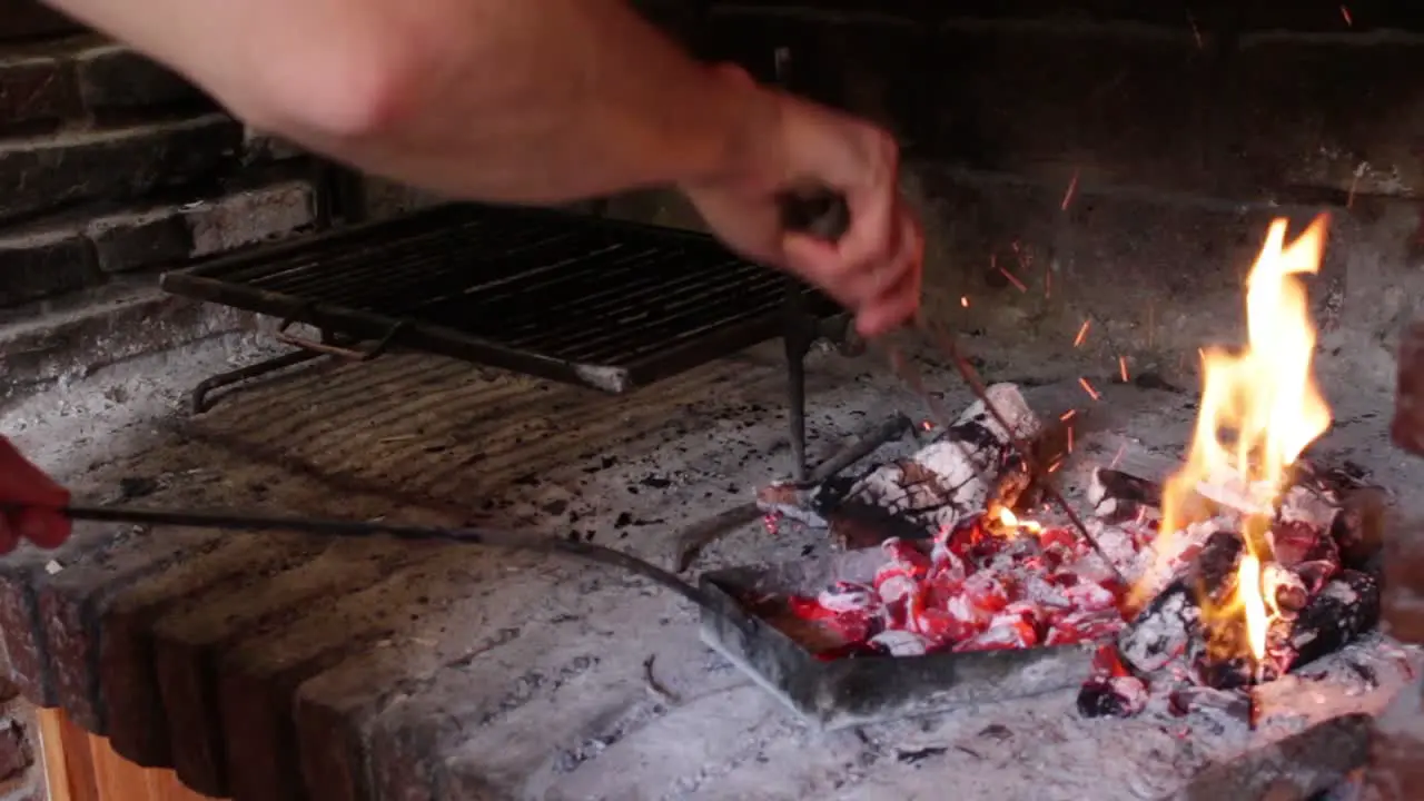 Static shot of hands distributing charcoal under grill