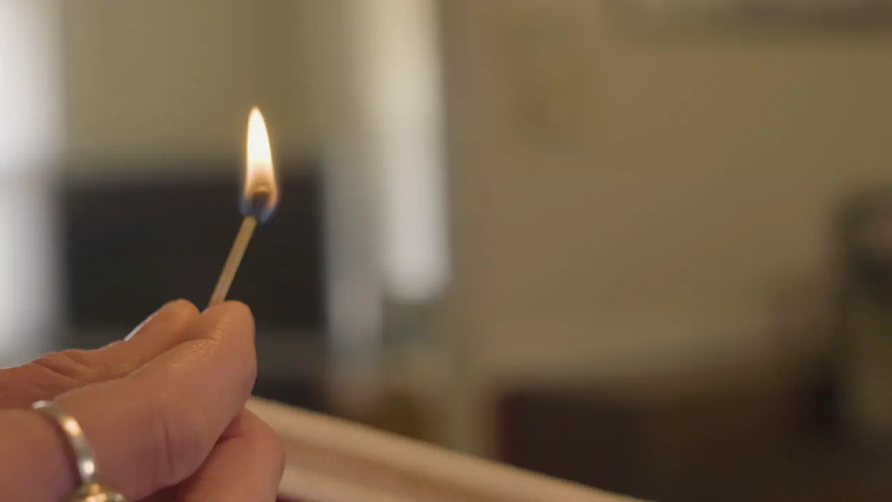 close up of woman holding a burning matchstick